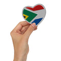 Hand holding a heart-shaped embroidered patch combining South African and Dutch flag colours, Two Homes One Heart South African Roots accessory.